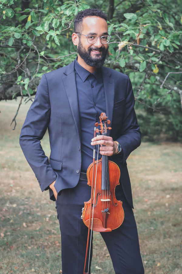 Male solo violin player for events standing outside on grass while posing to camera with violin before private event | Altus Entertainment